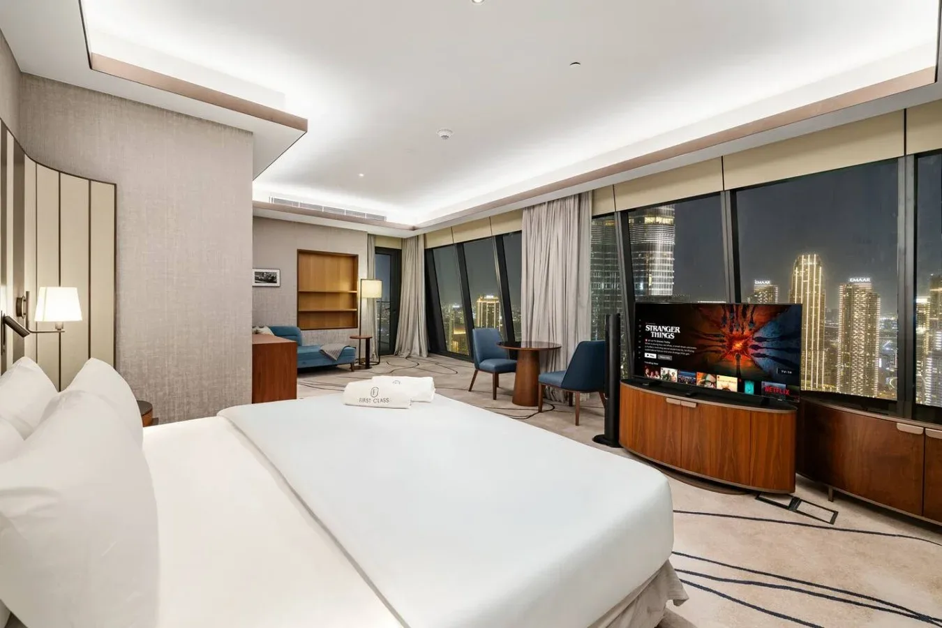 Un dormitorio moderno con una cama grande y ventanales que dan a la ciudad.