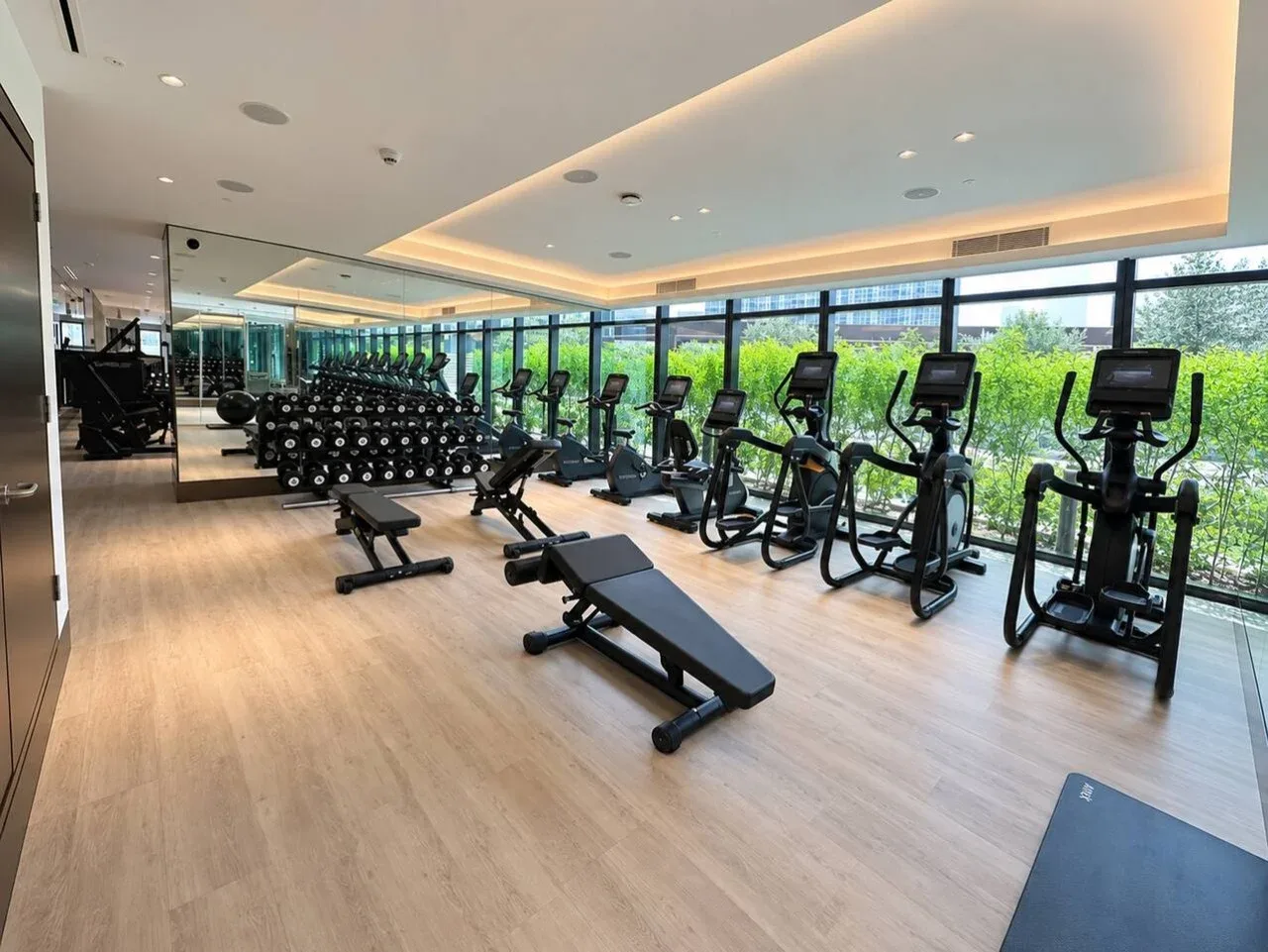 Una sala de ejercicio con bicicletas estáticas, pesas y bancos.