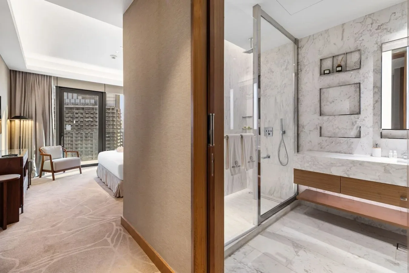 Un dormitorio con asientos y una ventana grande junto a un baño contiguo.
