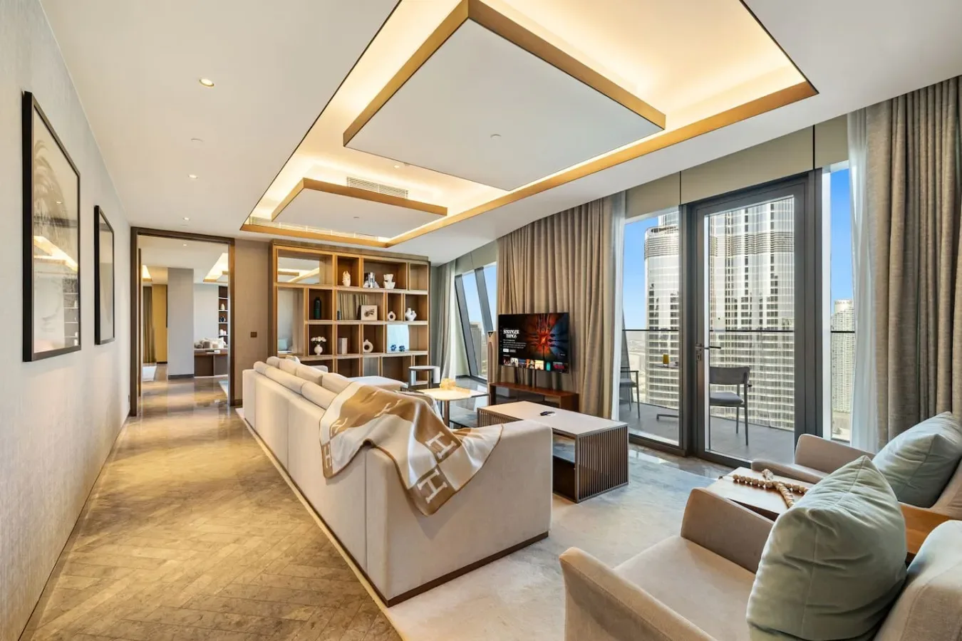 A modern living room with seating, a television, and large windows.