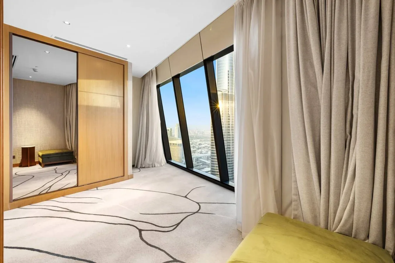 Un dormitorio luminoso con ventanas de suelo a techo y cortinas.