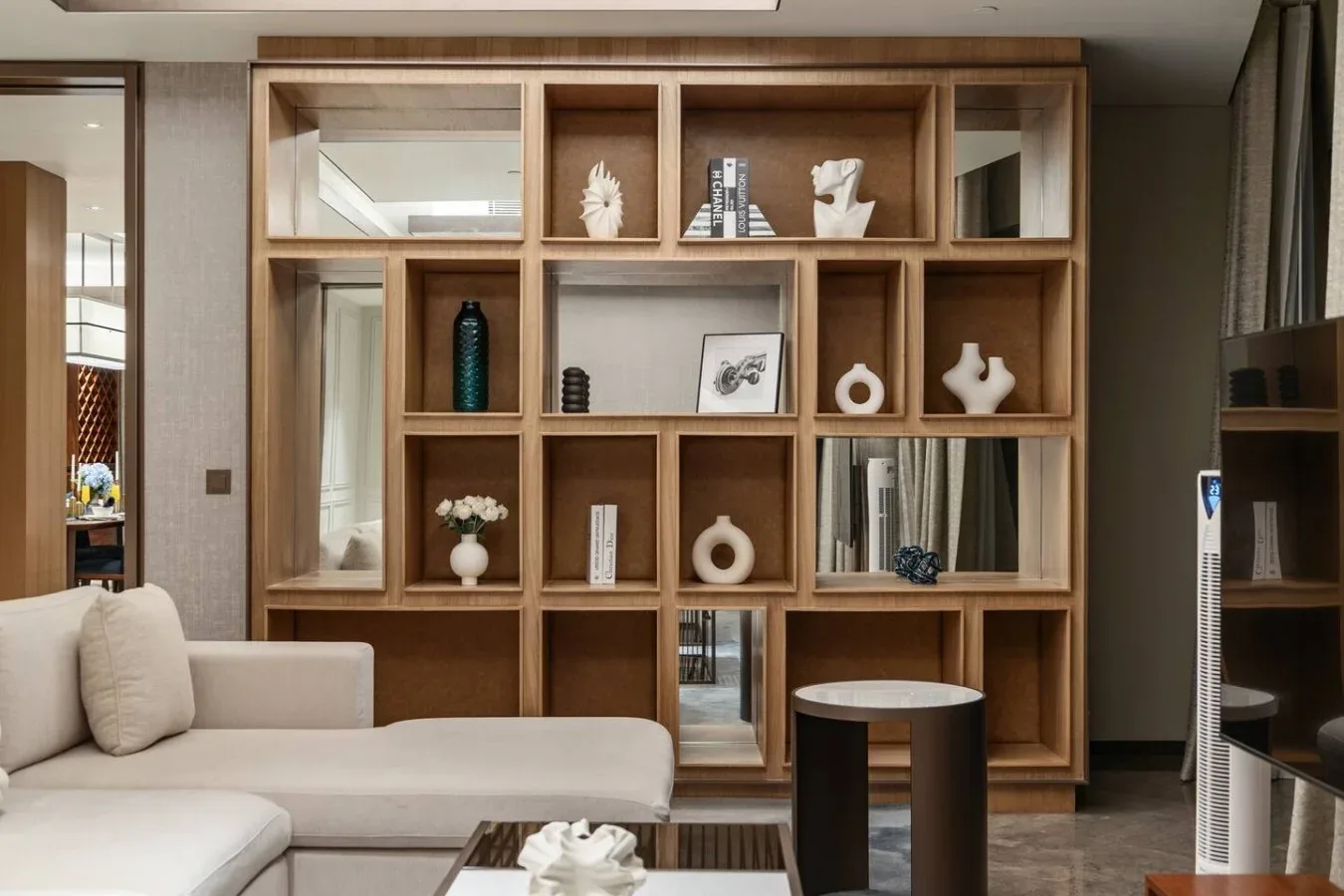 Una sala de estar con asientos claros y una gran estantería de madera.