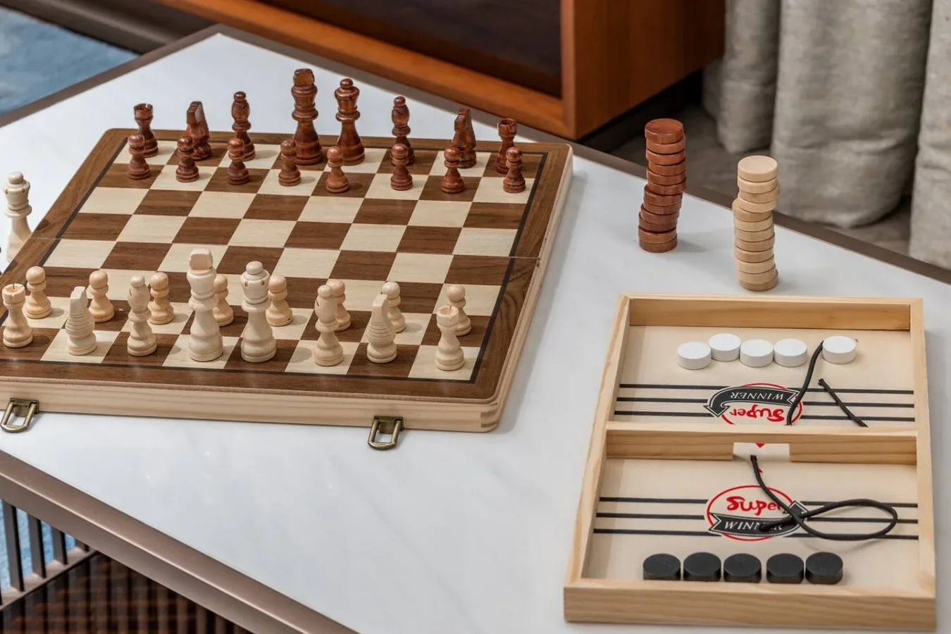 Una mesa muestra un juego de ajedrez y juegos de damas de madera.