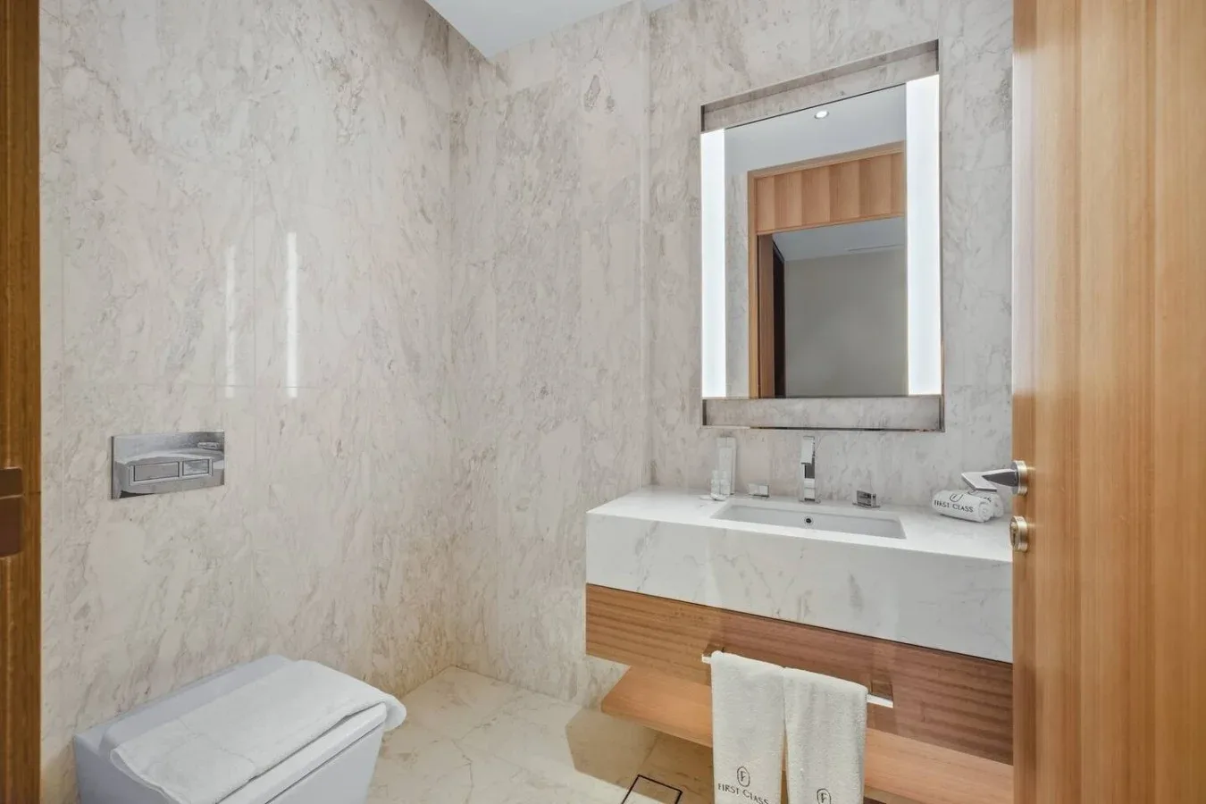 Un baño con un lavabo suspendido y un espejo grande.