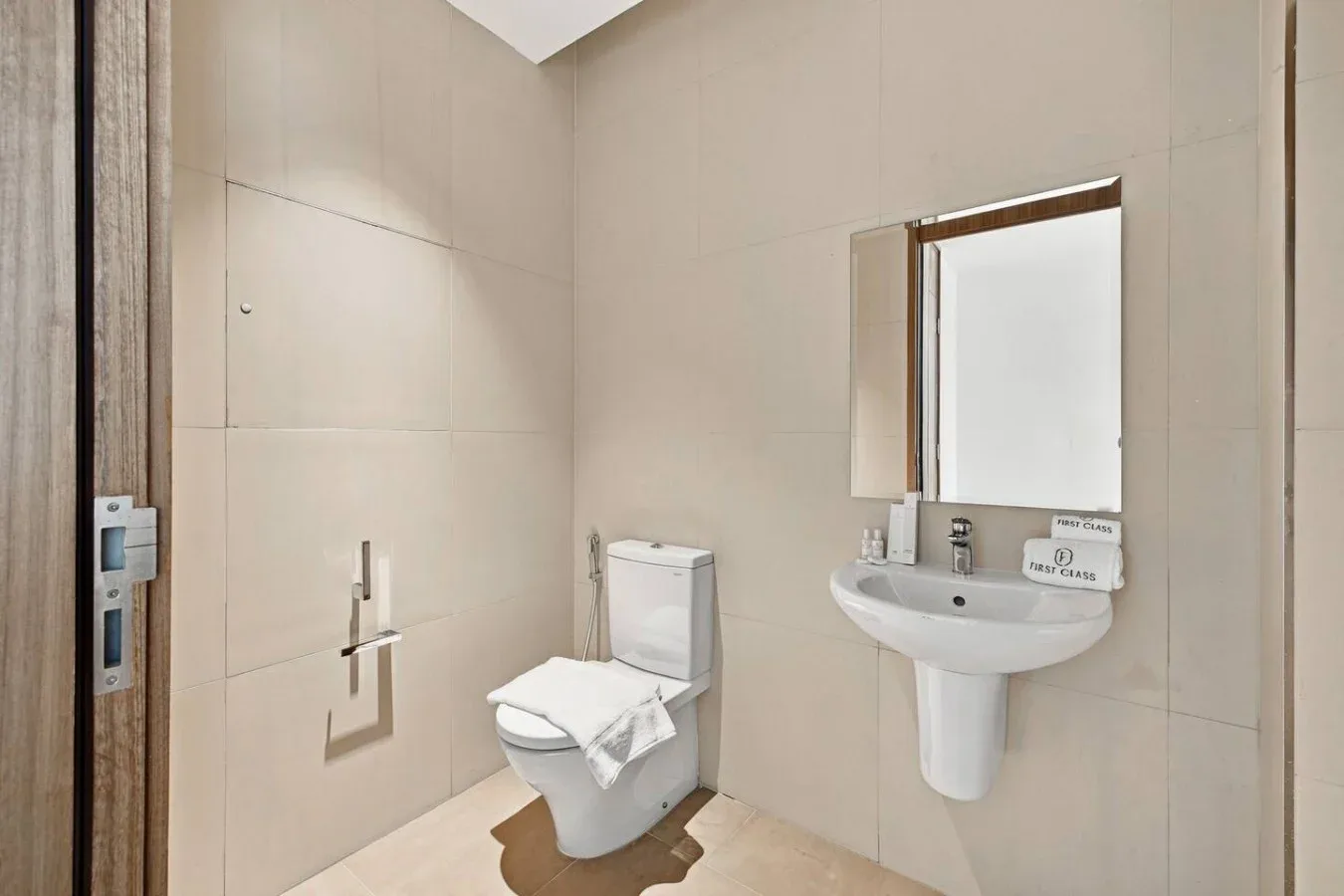 Un baño con un inodoro y un lavabo de pared debajo de un espejo.