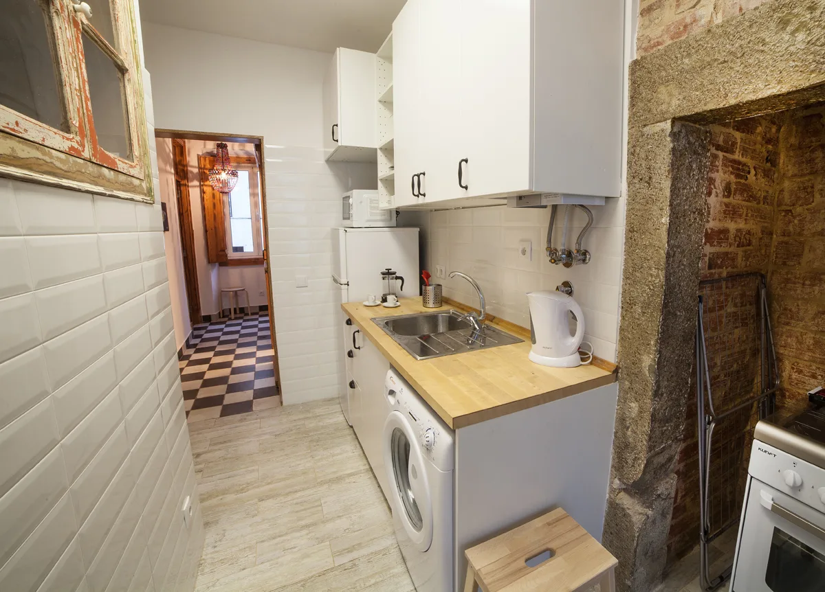 A compact kitchen with white cabinets, a countertop, and a washing machine.