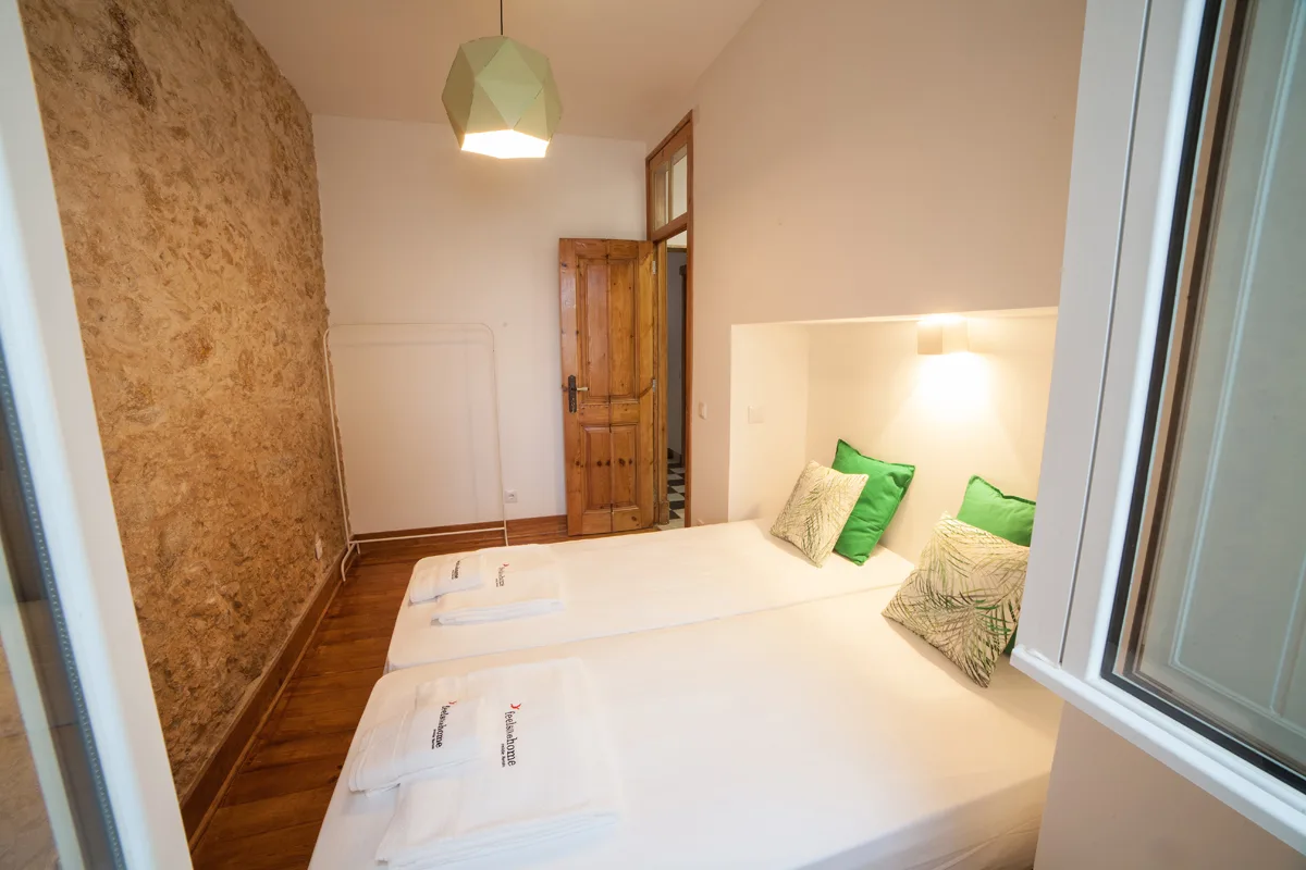 A bedroom with white beds and green accent pillows.