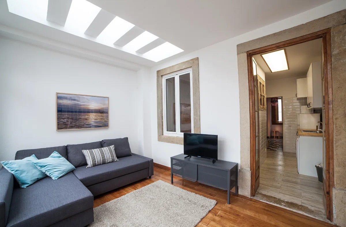 A living room with a sectional sofa, television, and doorway to the kitchen.