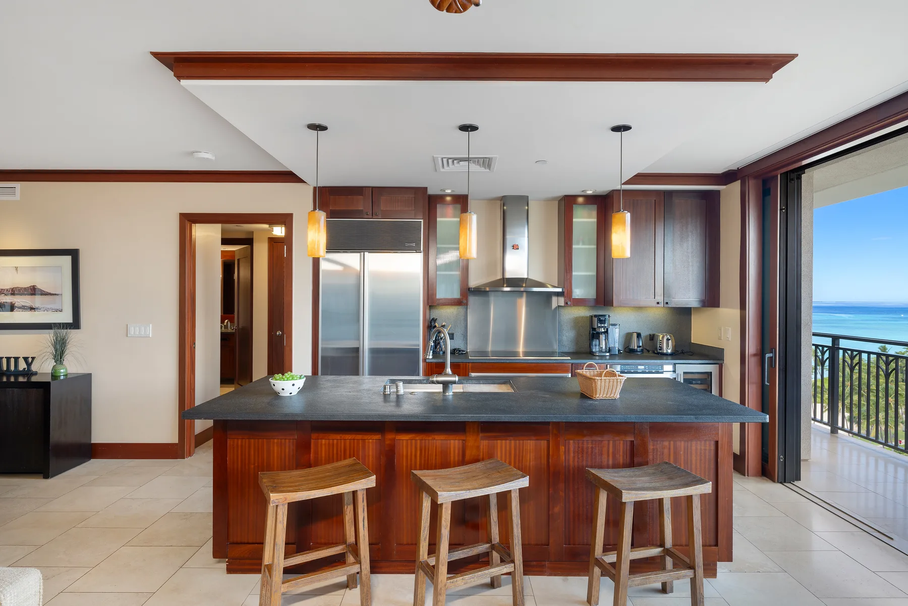 Una cocina abierta con una isla oscura y taburetes de madera.