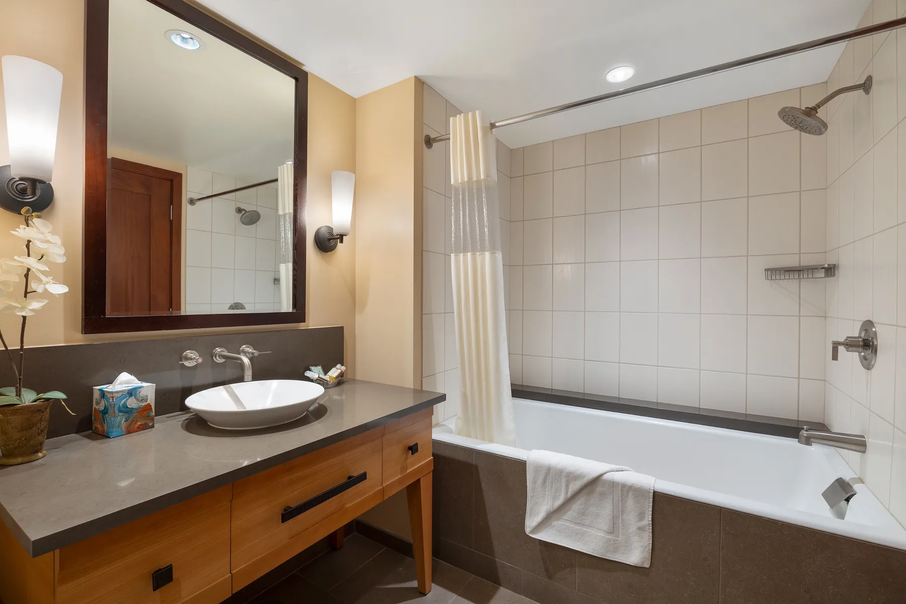 Un baño con un tocador junto a una bañera y ducha con azulejos.