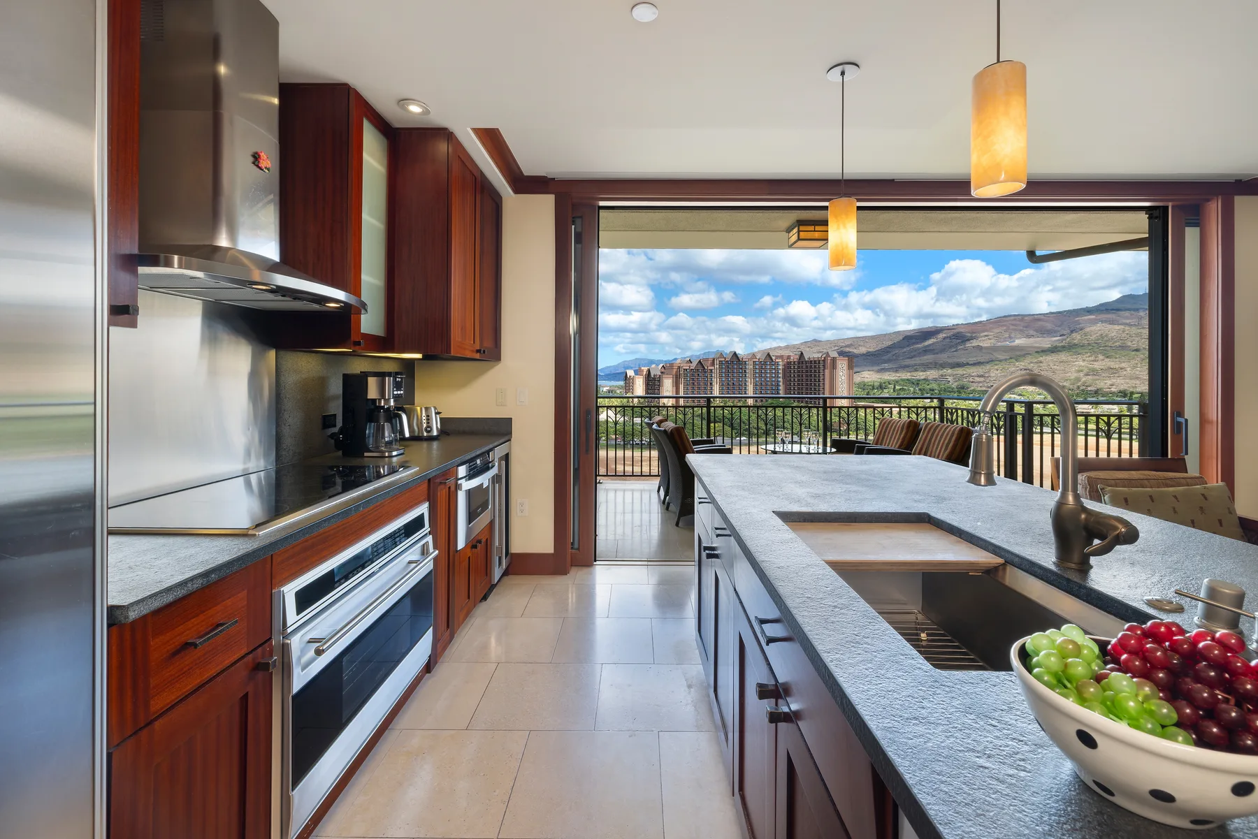 Una cocina moderna se abre a una terraza con vistas a las montañas.