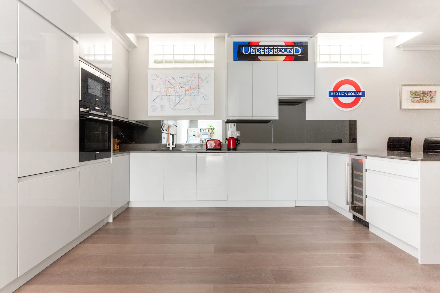 A bright modern kitchen with white cabinets and dark countertops.
