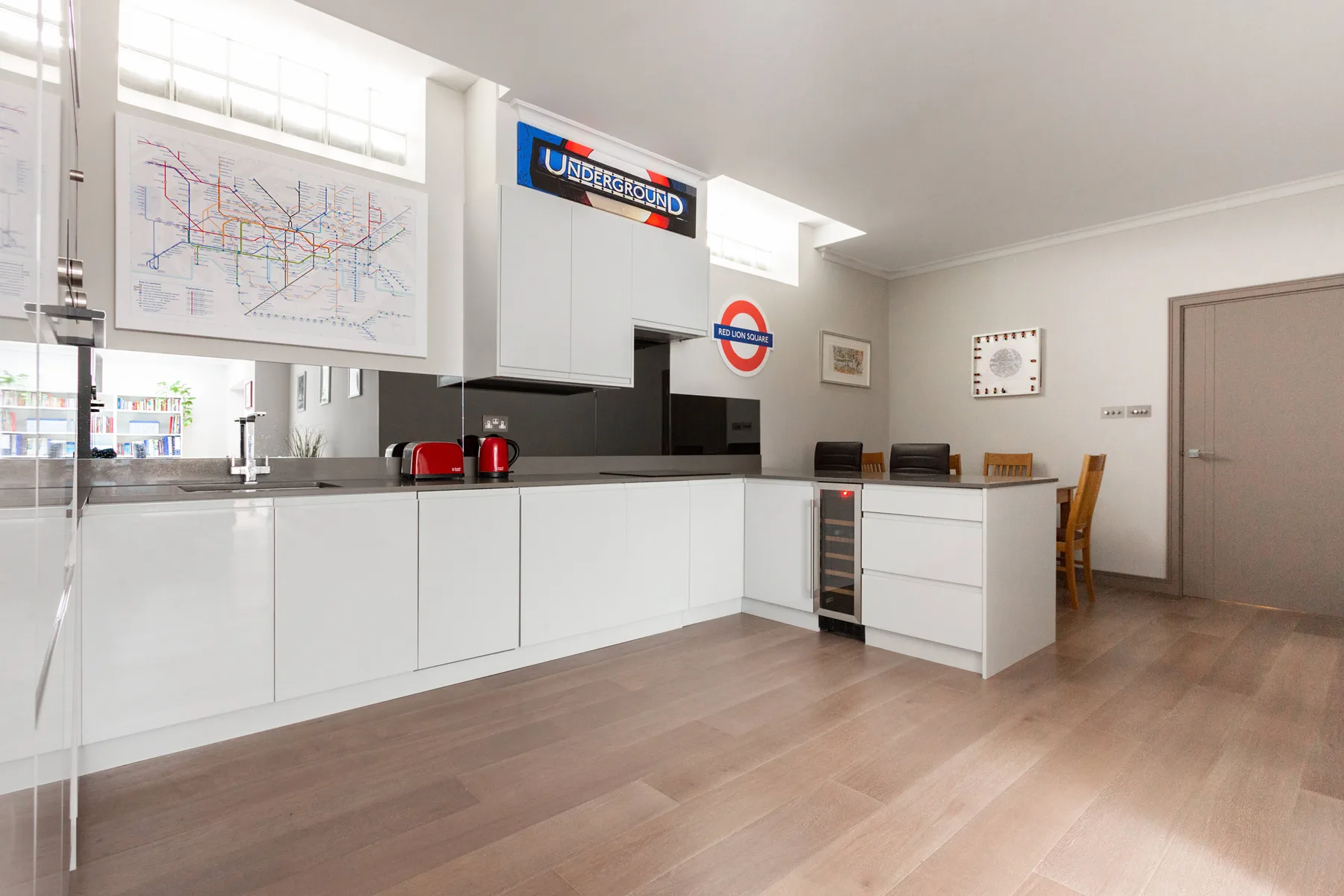A bright kitchen with white cabinetry, a countertop, and a small dining area.
