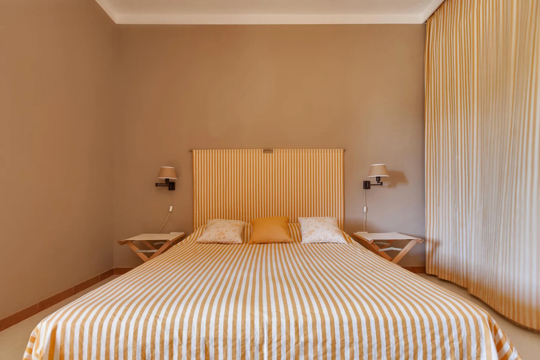 Un dormitorio con una cama cubierta con ropa de rayas y un panel de pared a juego.