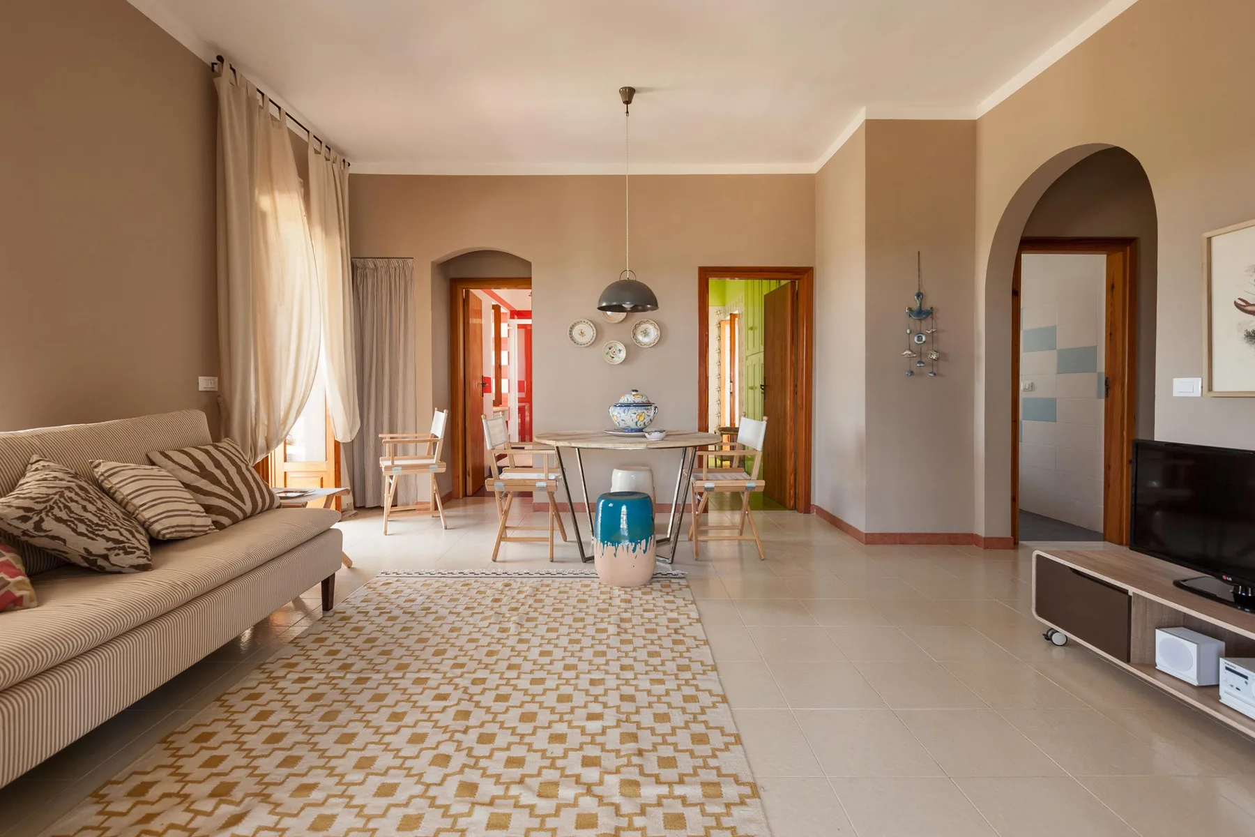 Una sala de estar y comedor con una alfombra estampada y una mesa junto a las ventanas.