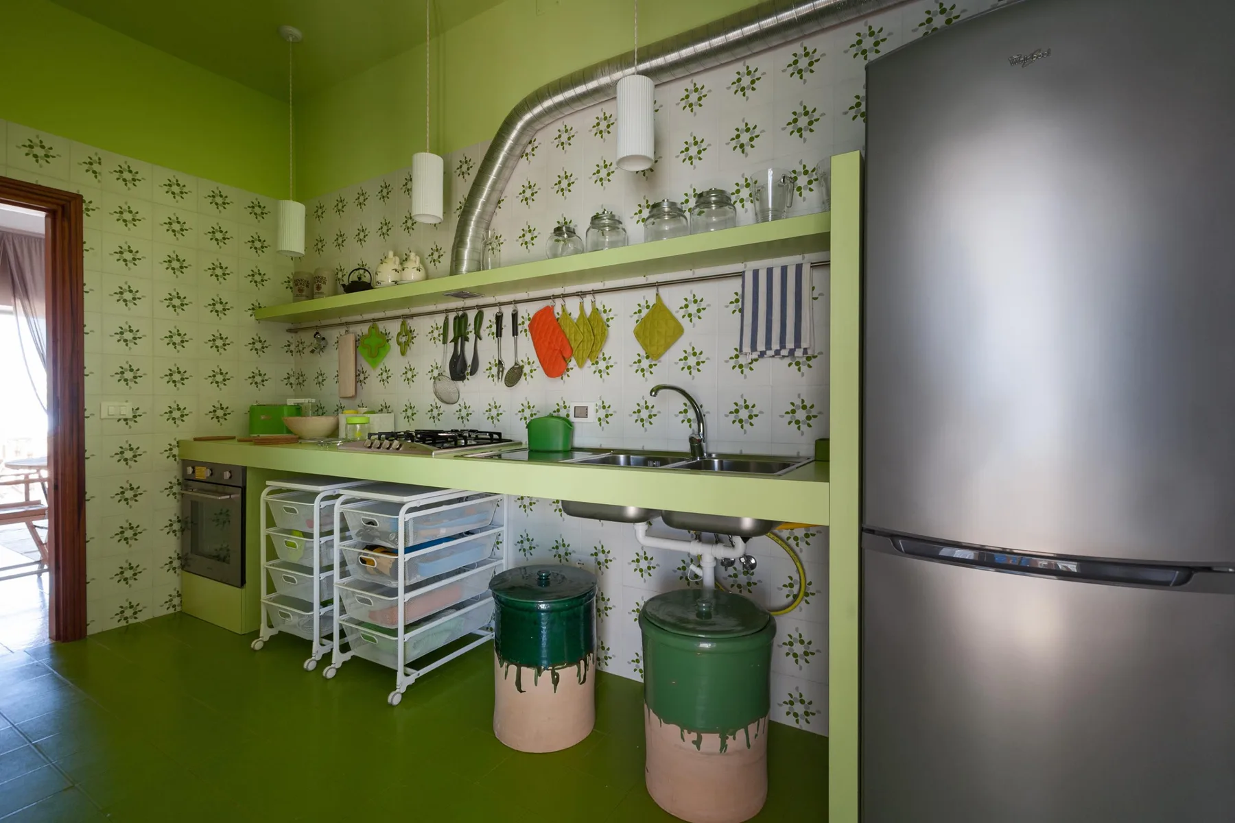 Una cocina verde luminosa con estufa, fregadero y refrigerador.