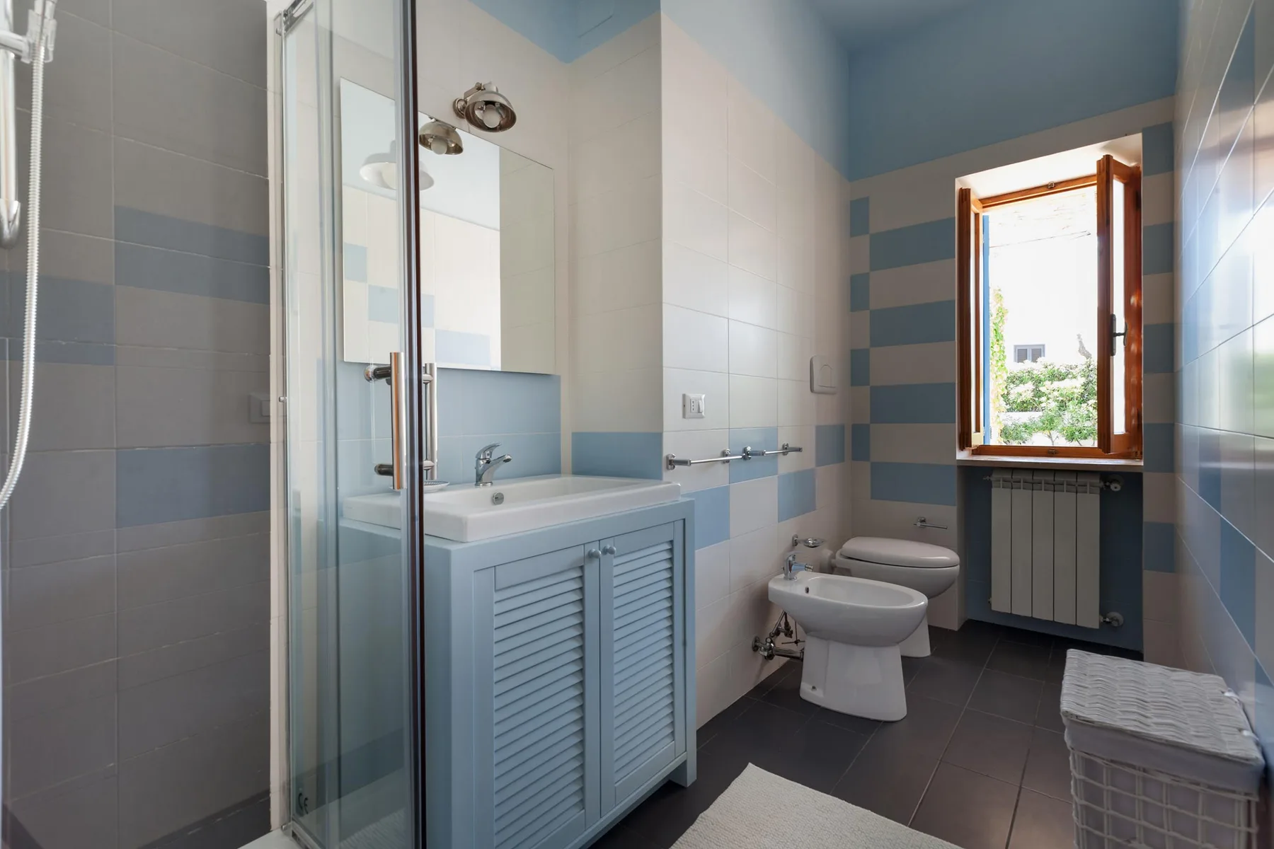 Un baño alicatado con ducha, lavabo, inodoro y ventana.