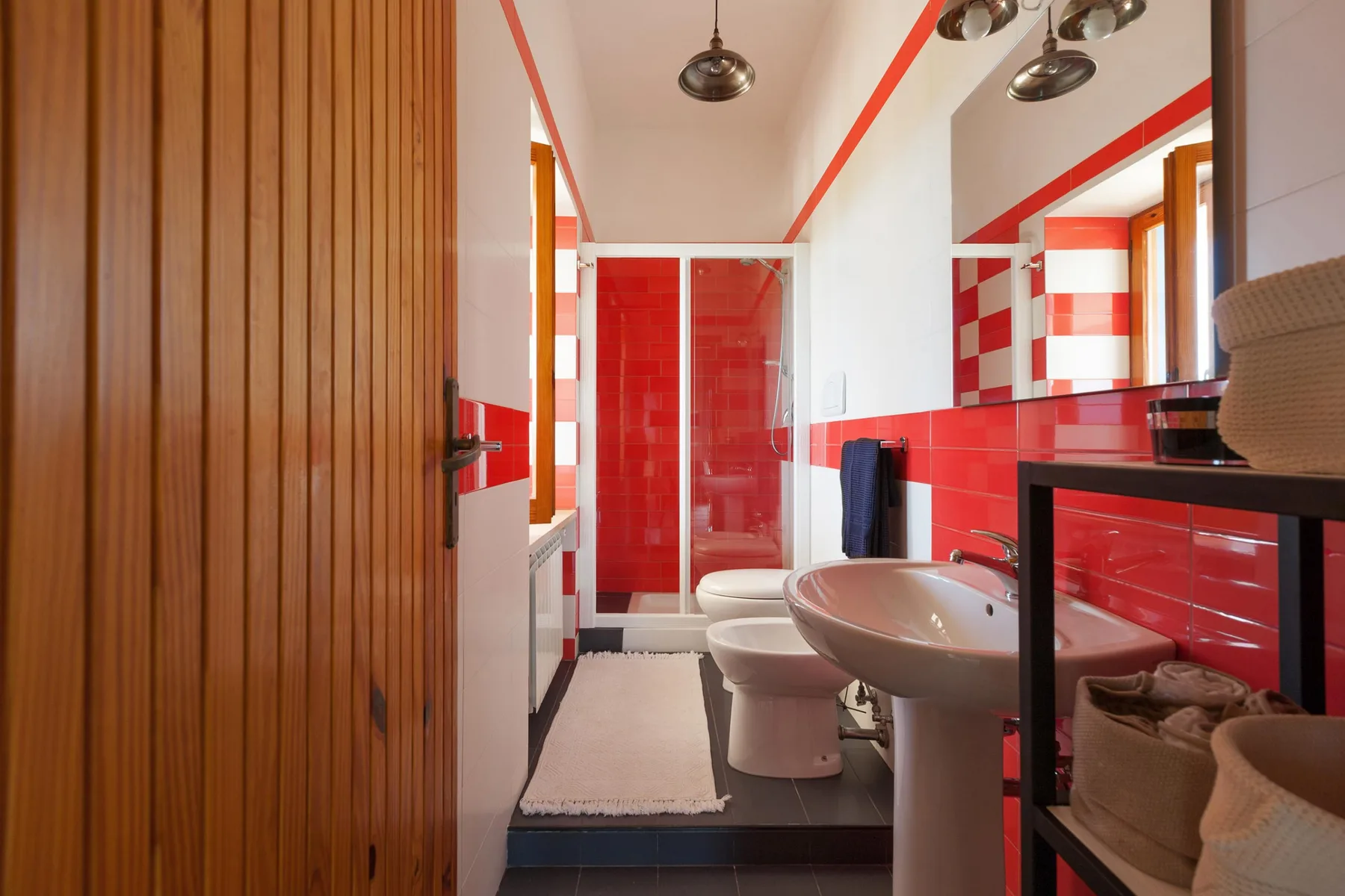 Un baño con azulejos rojos, un lavabo y una ducha.