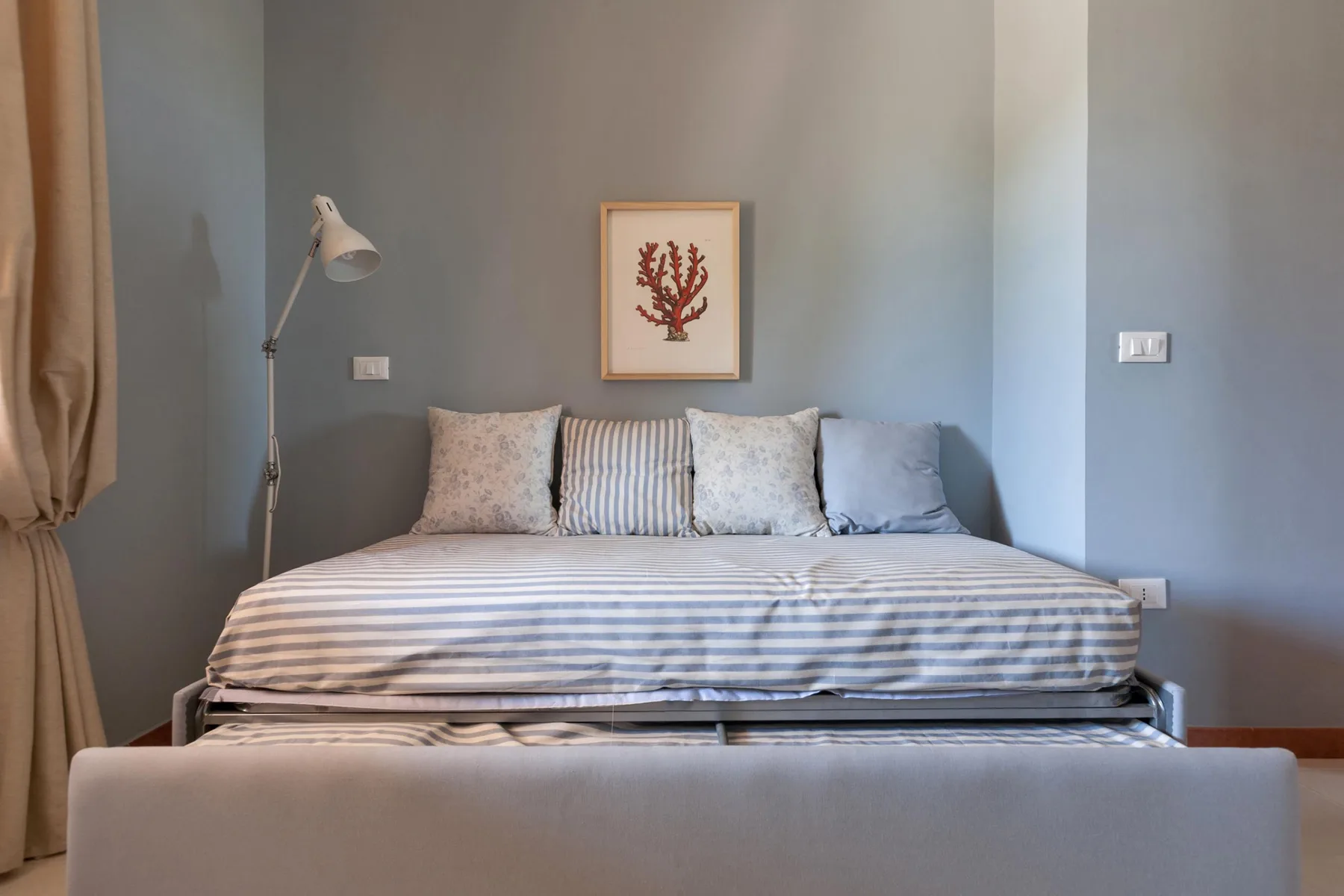 Un dormitorio con una cama vestida con ropa de rayas y cojines.