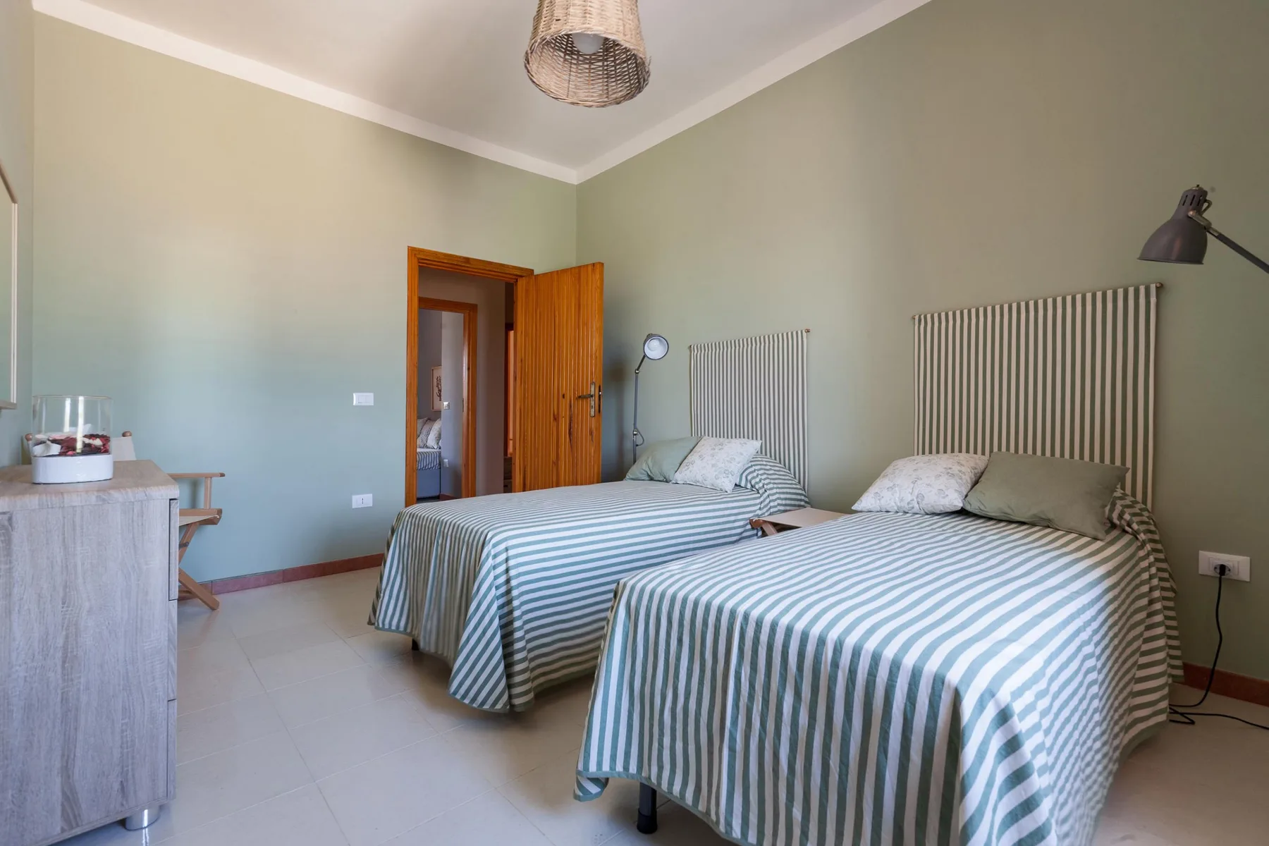 Un dormitorio con dos camas cubiertas con ropa de rayas y un escritorio pequeño.