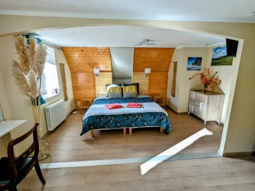 Chambre Printemps beneath exposed beams, with a large bed and mountain views.