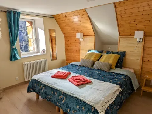 Chambre Printemps with exposed beams, patterned bedding, and mountain views.