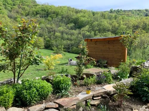 Garden with a timber structure and wooded hills.