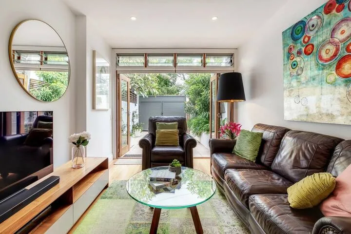 Una sala luminosa con asientos de cuero, una mesa de centro de vidrio y vistas al jardín.