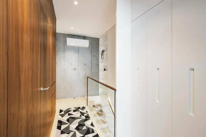 Un pasillo de baño moderno con una puerta de madera y baldosas geométricas.
