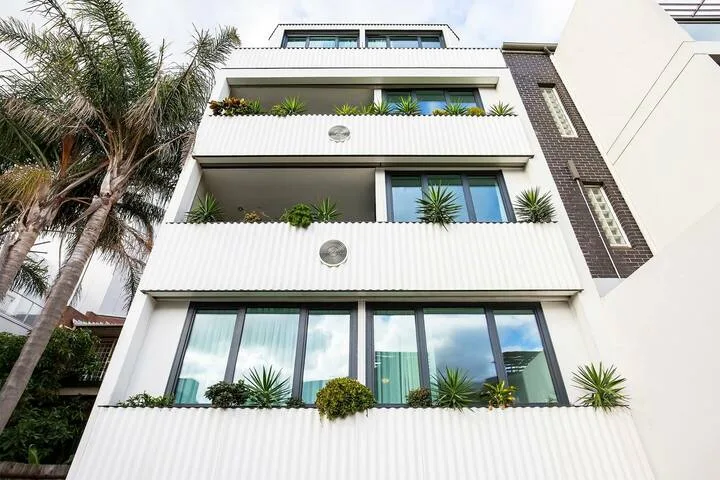 Un edificio moderno de varios pisos con balcones, ventanas y plantas en macetas.
