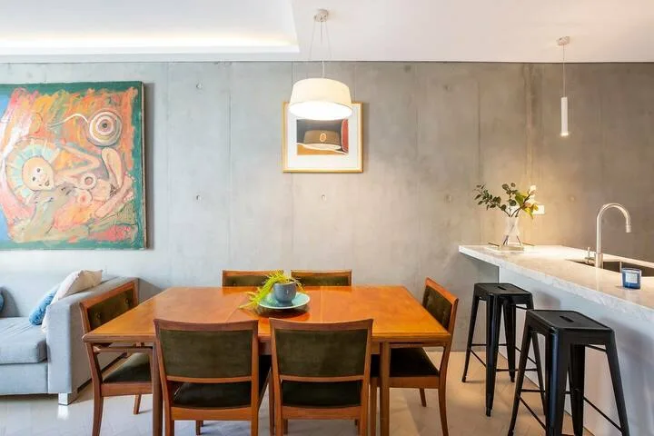 Un comedor con una mesa de madera y sillas junto a una encimera.