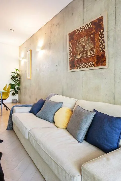 Una sala de estar con un sofá claro y alargado y arte enmarcado en la pared.