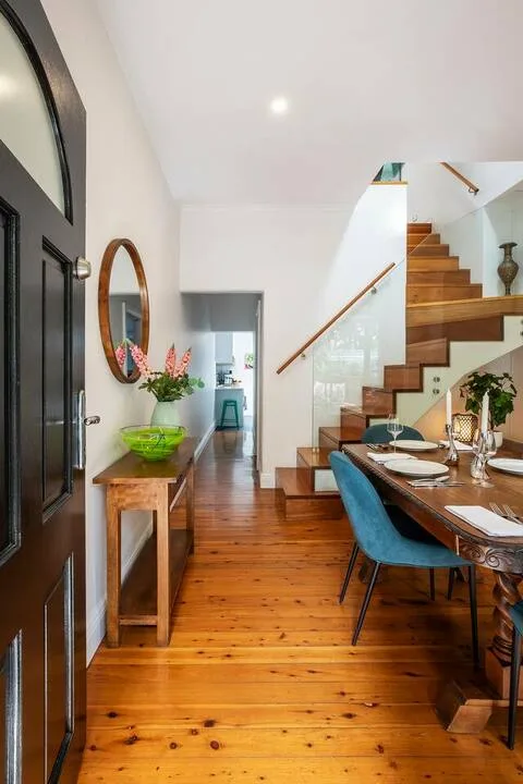 Comedor junto a una escalera de madera, con una mesa y asientos azules.