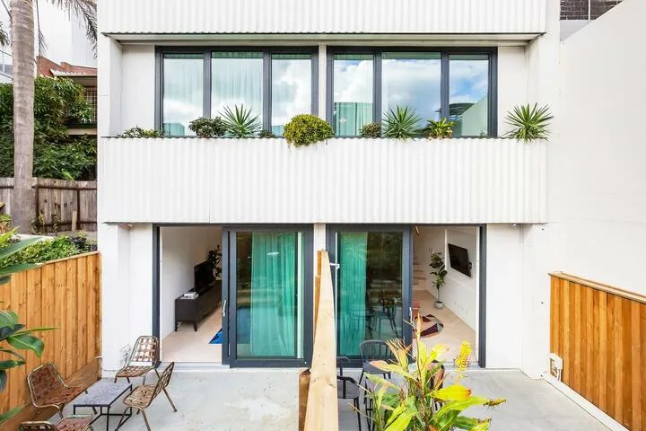 Un edificio moderno de dos plantas con grandes ventanas y un patio a nivel del suelo.