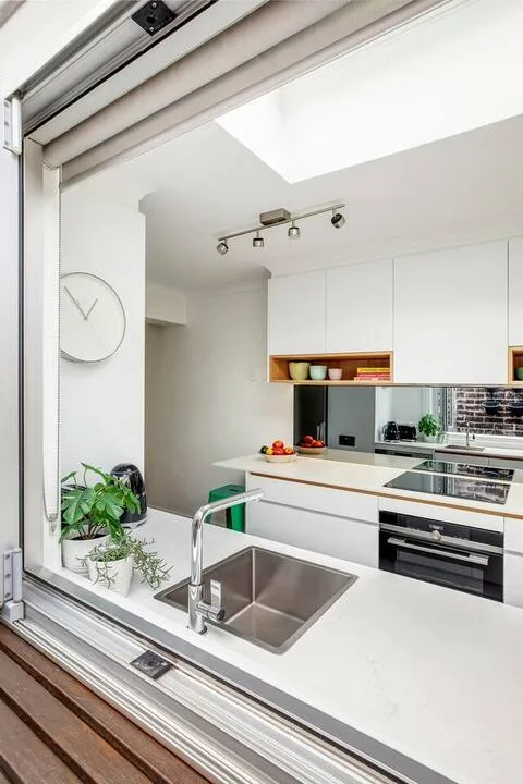 Una cocina moderna y luminosa con gabinetes blancos y un fregadero de acero inoxidable.
