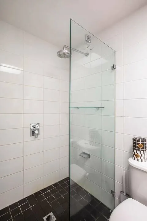 Baño con azulejos, mampara de vidrio y un inodoro.