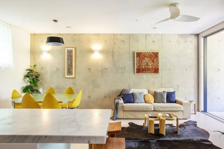 Una luminosa sala de estar y comedor con asientos, una mesa y ventanales.