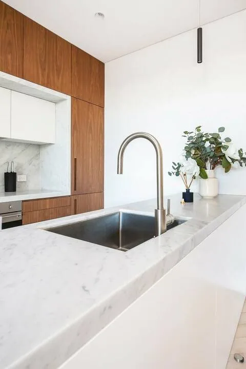 Una cocina moderna con encimera de mármol, fregadero y grifo curvo.