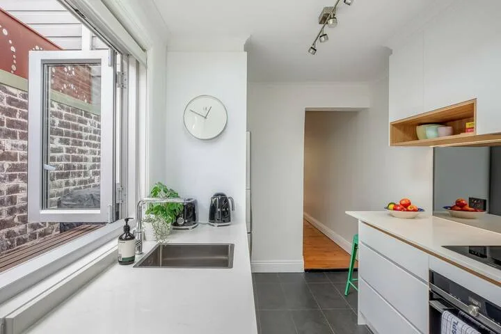 Una cocina luminosa con fregadero, encimera y una puerta abierta.
