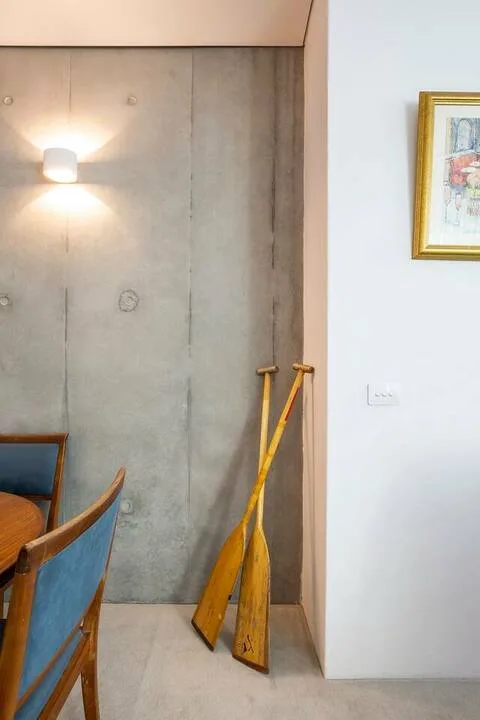 Un comedor con asientos de madera y remos apoyados contra una pared de hormigón.