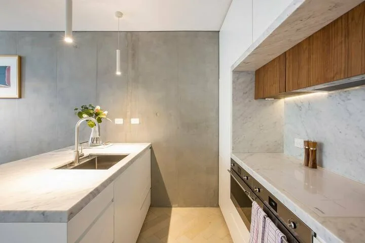 Una cocina moderna con una isla larga y gabinetes de madera en la pared.