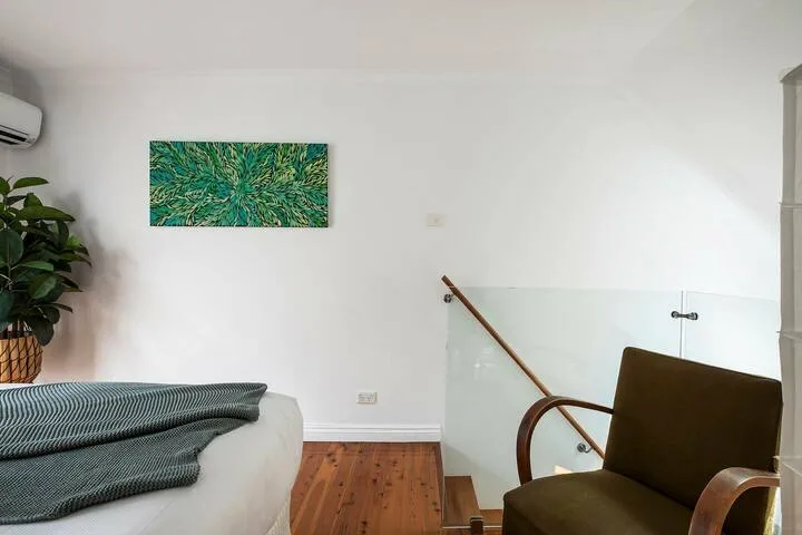 Un dormitorio con una cama, una silla y una barandilla de vidrio.