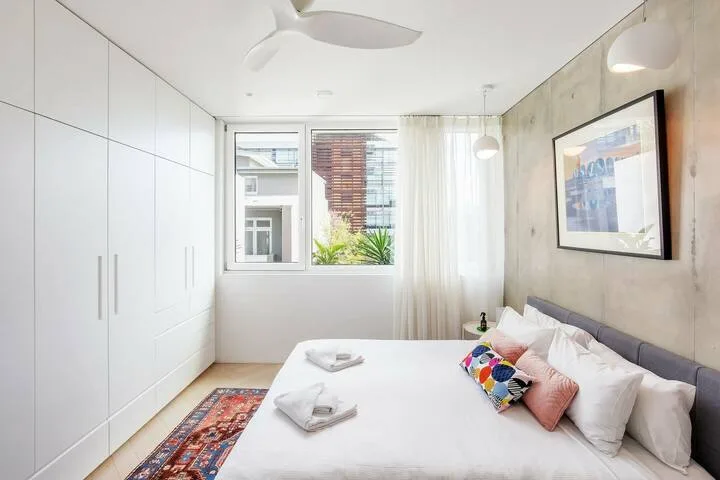 Un dormitorio luminoso con una cama grande, armarios empotrados y una ventana.