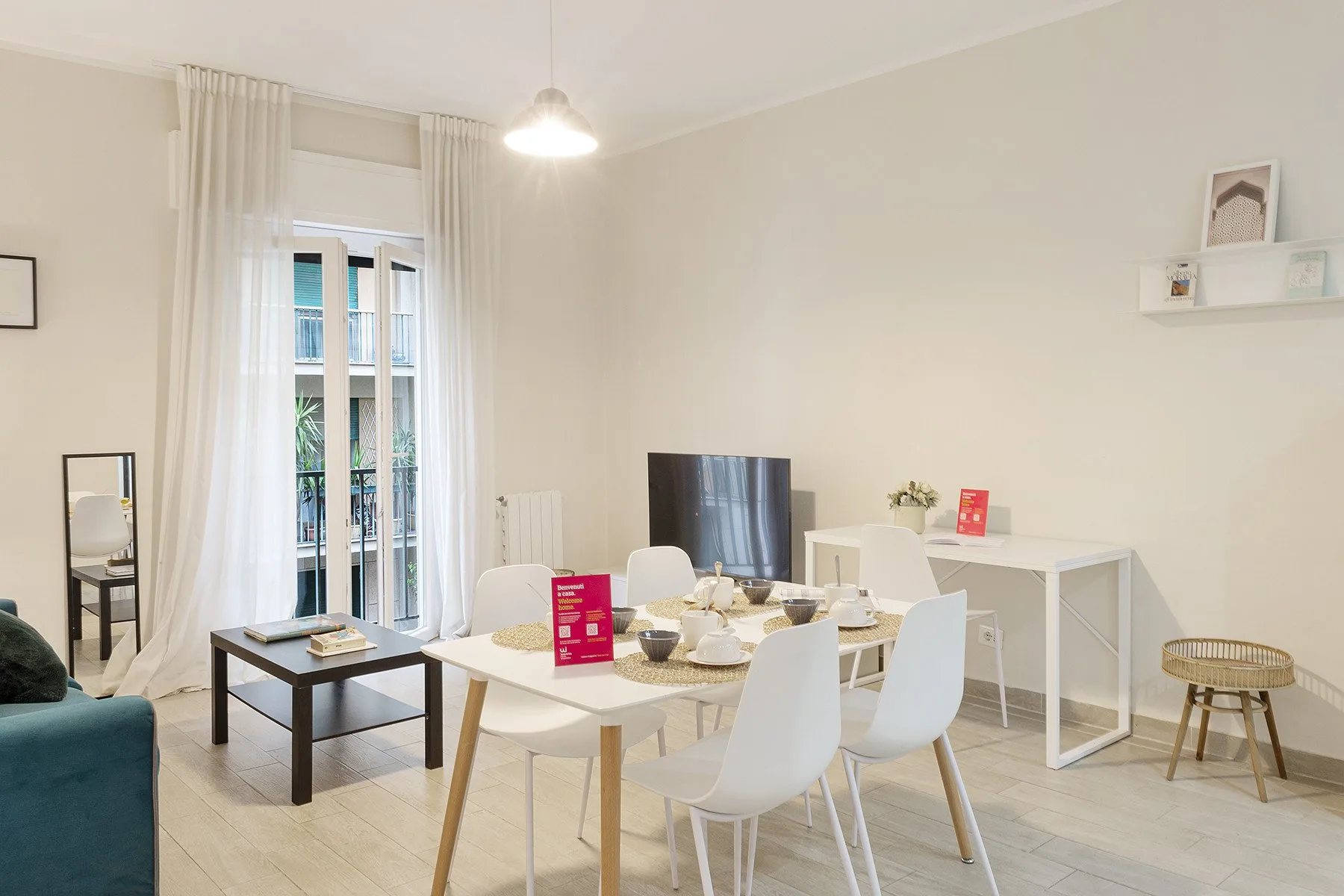 Una luminosa zona de comedor y estar con una mesa puesta junto a un televisor.