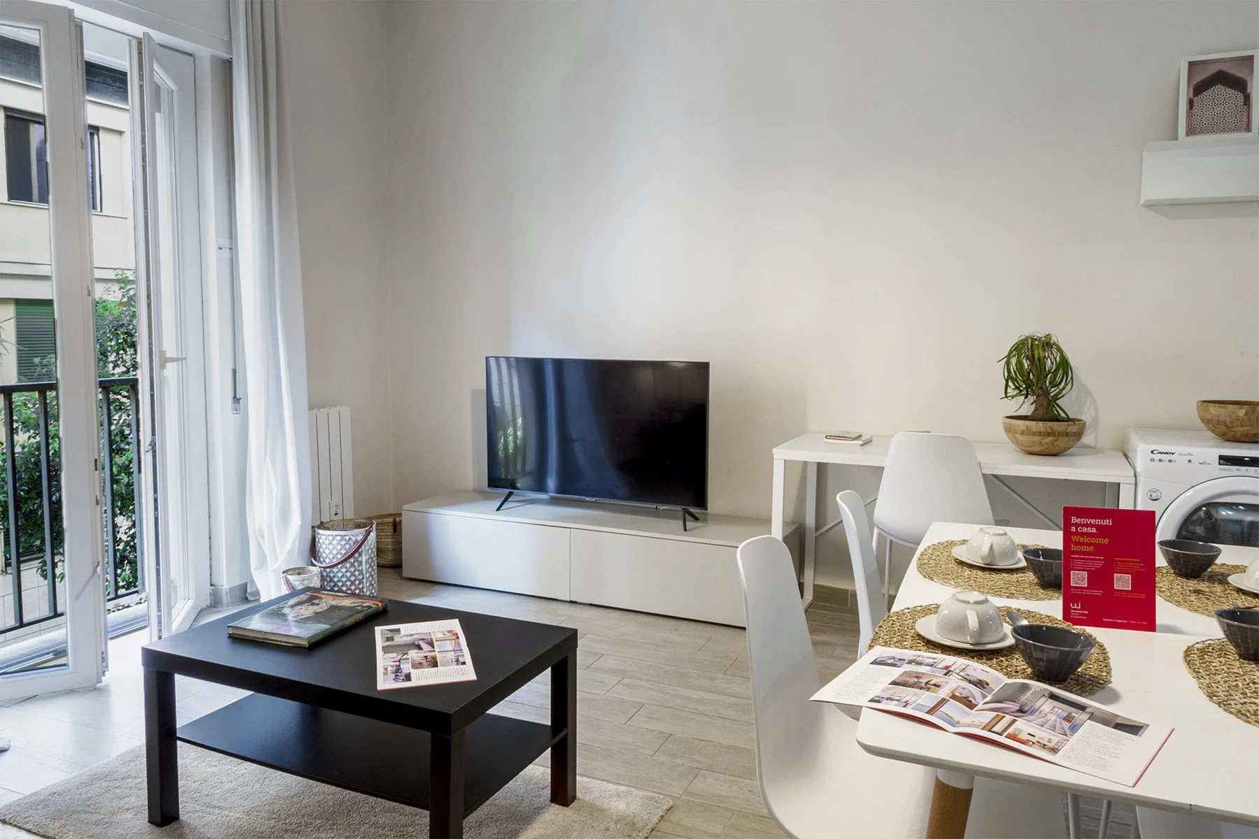 Una luminosa sala de estar y comedor con un televisor y una mesa puesta.