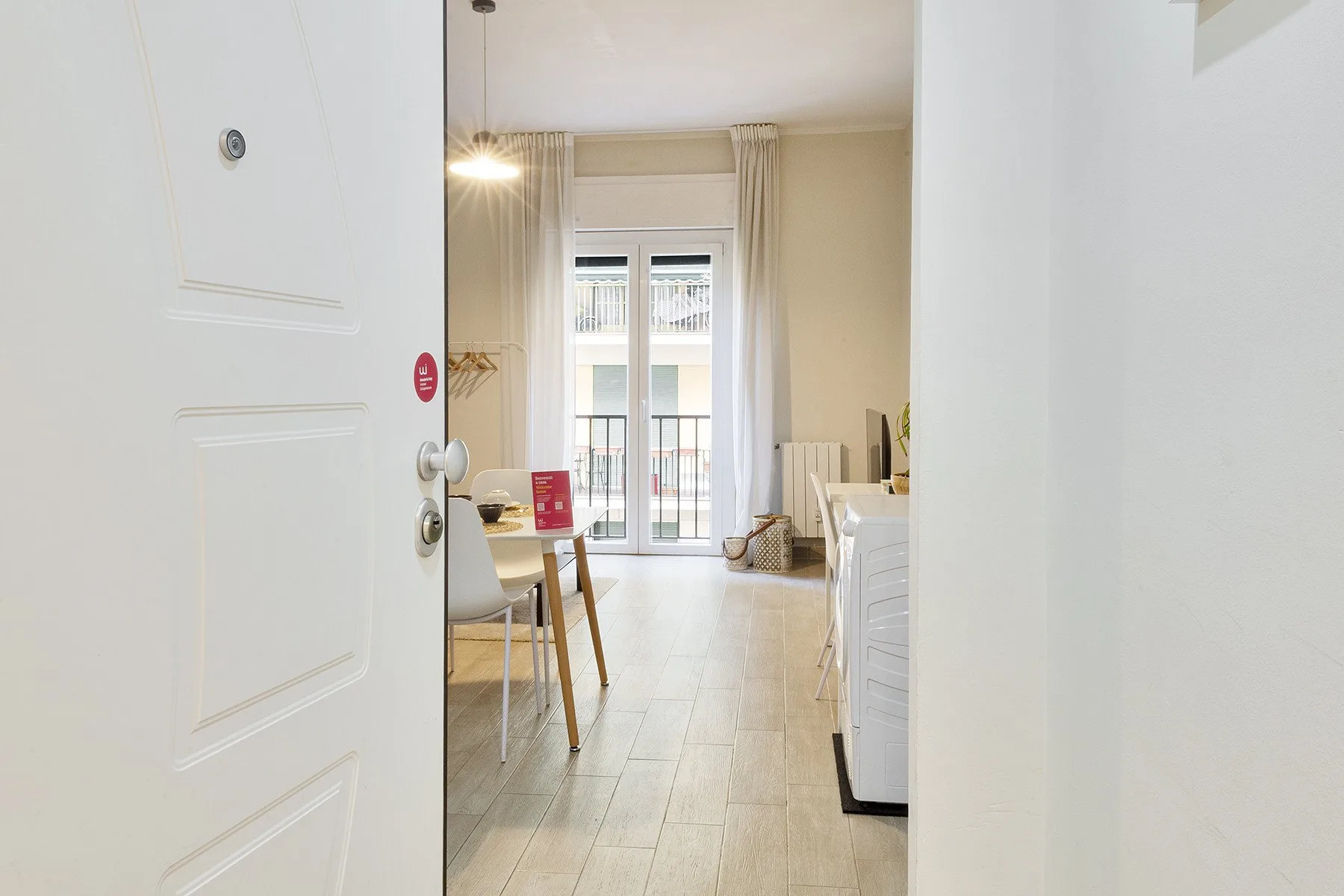 Una habitación luminosa con una mesa y asientos junto a una puerta de vidrio al balcón.