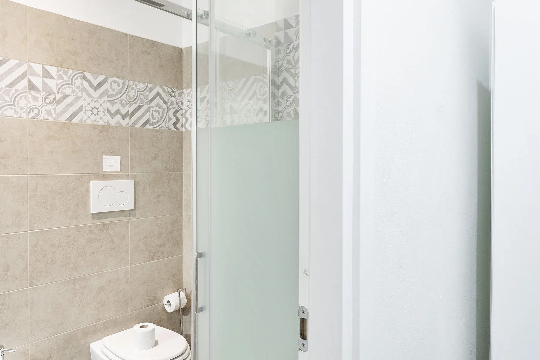 Un baño con azulejos, una ducha de vidrio y un inodoro.