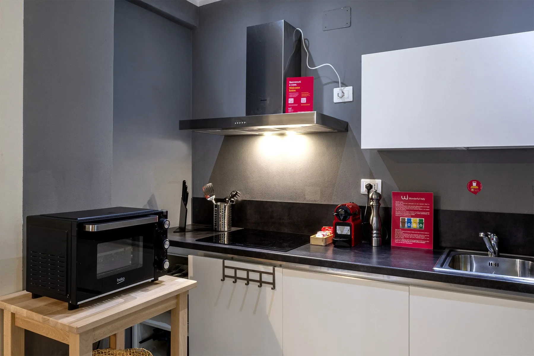 Una cocina compacta con un microondas sobre una mesa de madera y una encimera oscura.