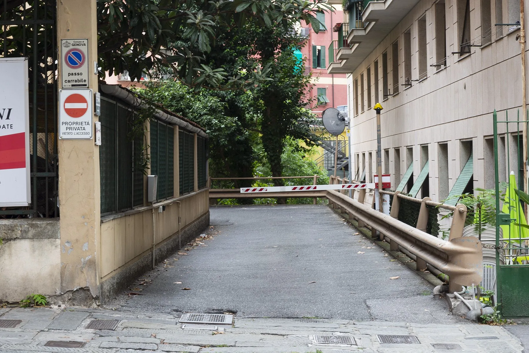 Un camino pavimentado conduce a una barrera bajada entre edificios.