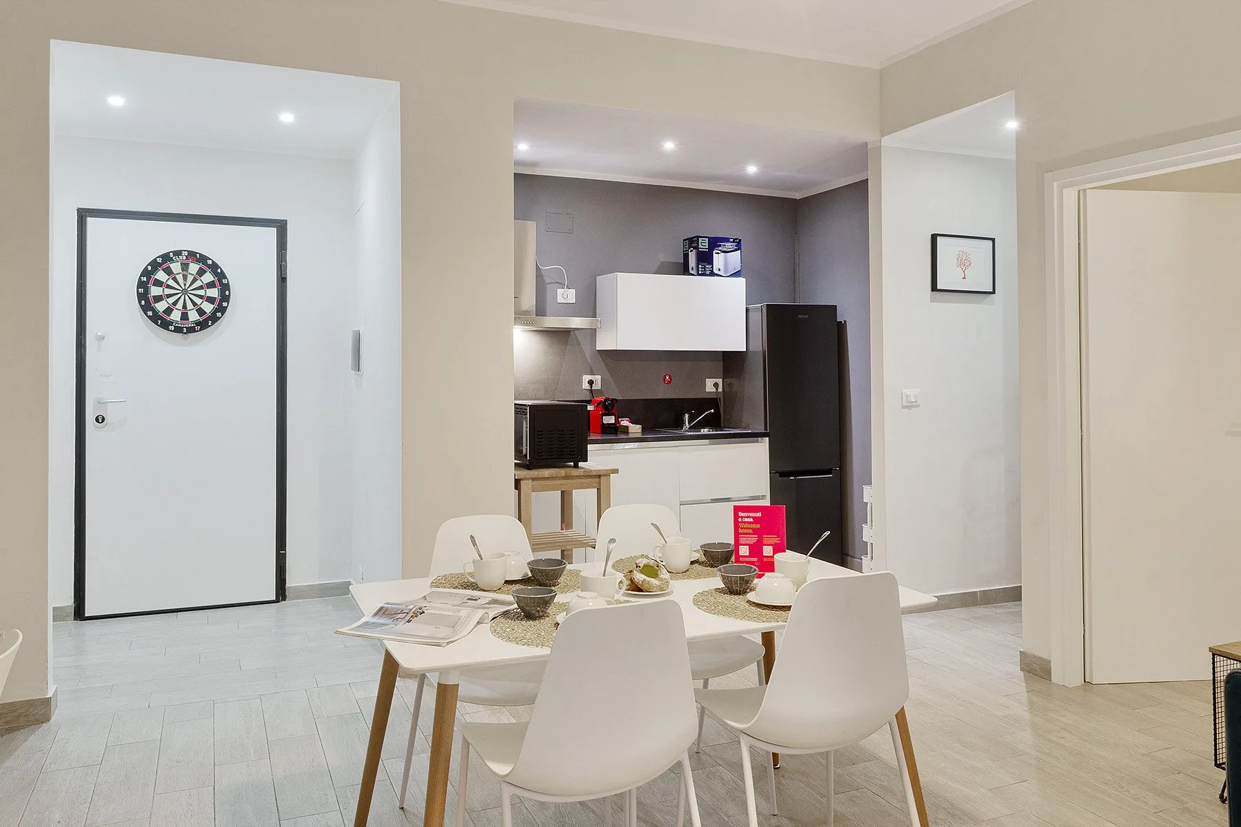Un comedor con una mesa blanca y sillas está frente a una cocina compacta.